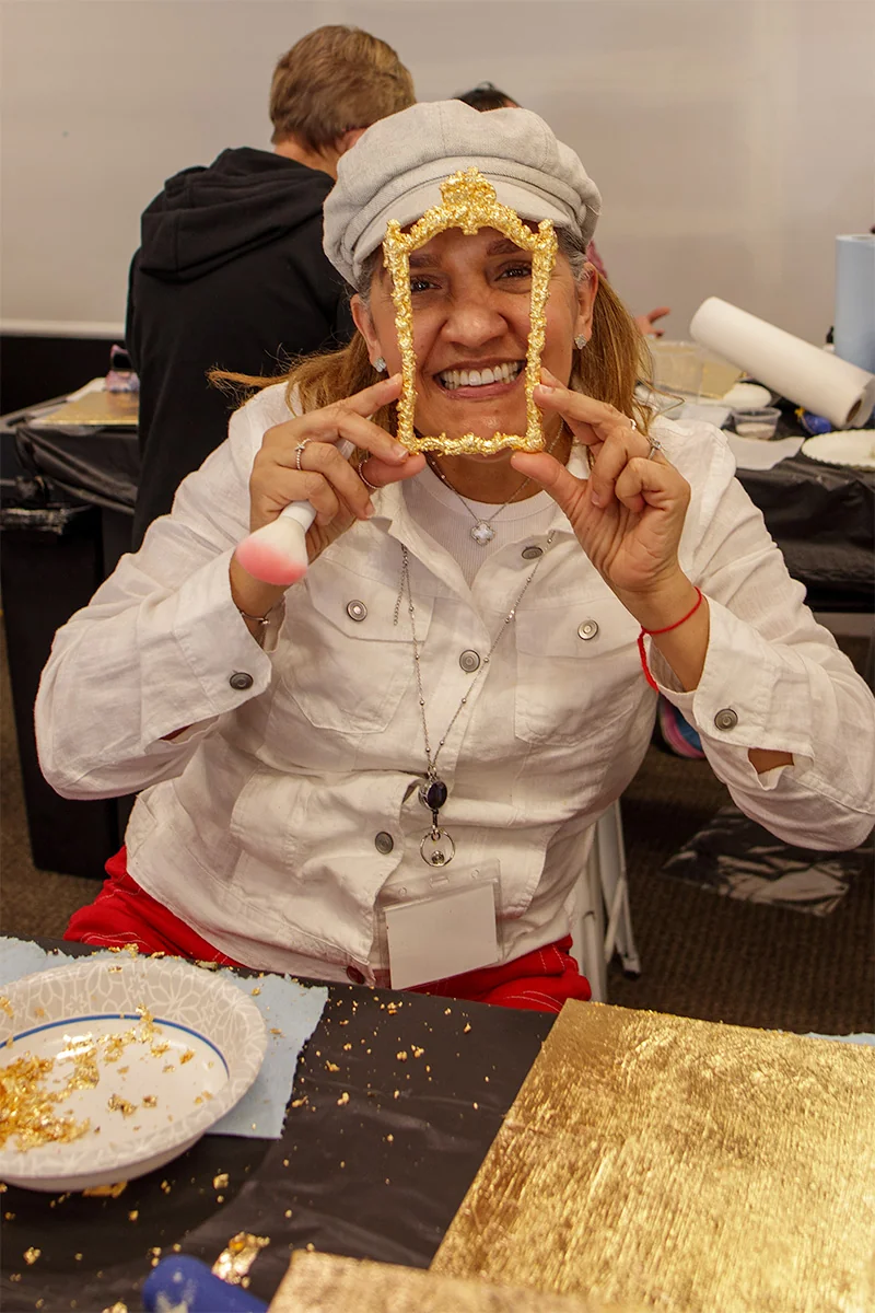 Student holding up a finished piece with gold-leaf frame in Kacha advanced workshop